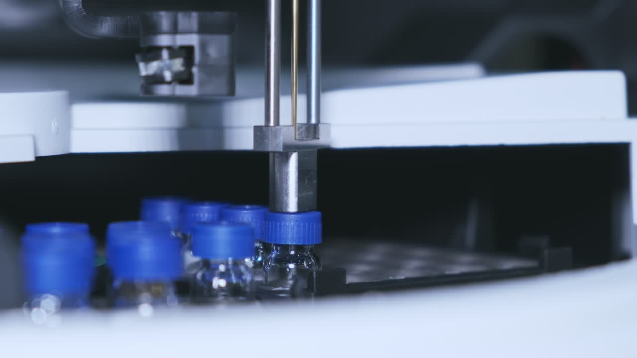 los viales de vidrio con tapas azules se rotan en el mostrador automático de hplc.
