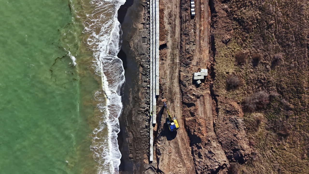 Costruzione di una nuova passerella lungo la costa con operai e macchinari presenti in riva all'oceano durante il giorno