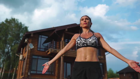 Una-Mujer-Delgada-Y-Hermosa-Con-Ropa-Deportiva-En-El-Fondo-De-La-Casa-En-El-Césped-Realiza-Saltos-Para-Entrenamiento-Cardiovascular-Y-Quema-De-Grasa