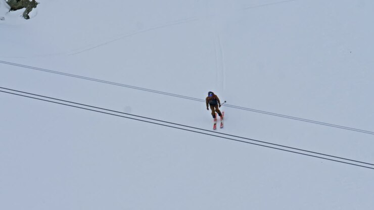 Cinematic footage of a freeride skier charging fast down a steep alpine run. Aggressive skiing, speed, control, and raw mountain energy in a high-altitude winter environment