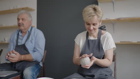 a group of senior women and a man together learn to make pottery on a potter's wheel. making utensils on a retired potter's wheel