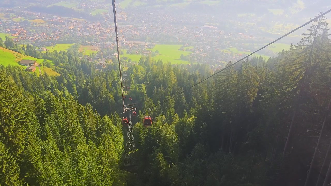 Paesaggio panoramico di Kitzbühel, Austria, da una funivia, con strade del villaggio, campanili, campi verdi e montagne che circondano la famosa località turistica tirolese in una scena di viaggio estiva