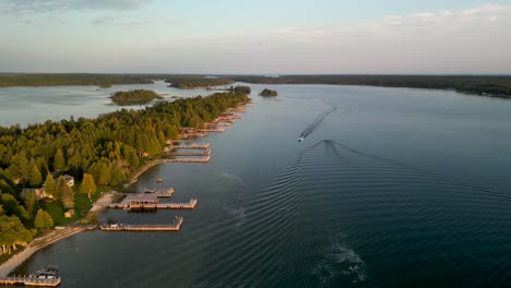 Aerial-ascending-view-of-boats-on-water-and-coastline-golden-hour,-Les-Cheneaux-Islands,-Michigan