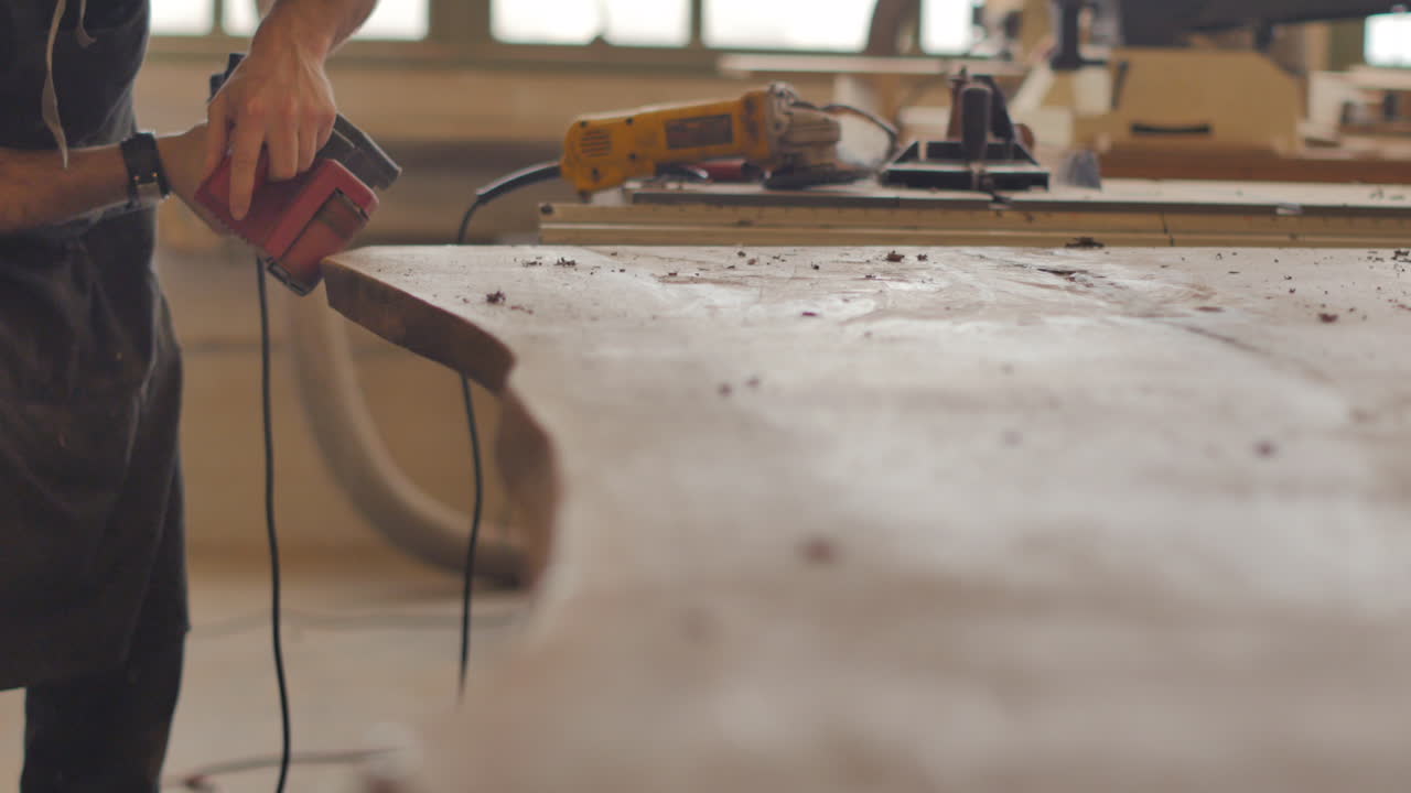un carpintero está lijando una mesa personalizada hecha a mano de madera natural