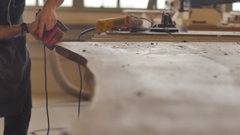 un carpintero está lijando una mesa personalizada hecha a mano de madera natural