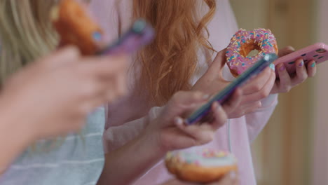 close up teenage girl using smartphone browsing social media texting friends hanging out eating donuts