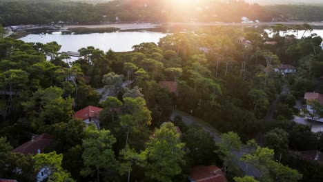 Drone-flys-over-Hossegor-Seignosse-France-Lakeside-Town-with-many-trees-and-homes-with-morning-sunlight-shining-over