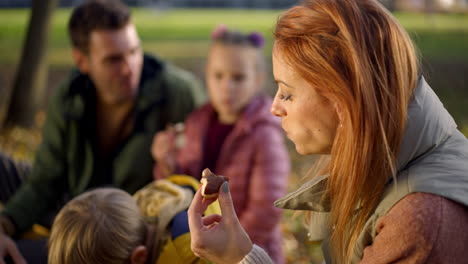 family enjoying a snack in the park during autumn