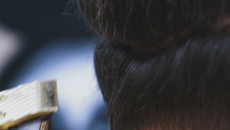 hairdresser does haircut to young client with golden machine