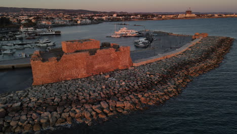 drone reveal pafos castle basking in the warm glow of setting sun, cyprus