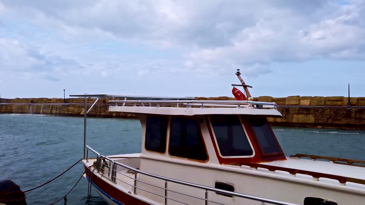 White lonely boat at the pier in the city. Rainy day. Close up. Slow motion. Kyrenia, Cyprus