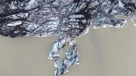 Top-down-aerial-view-of-melting-icy-rocky-glacier-landscape-in-Iceland
