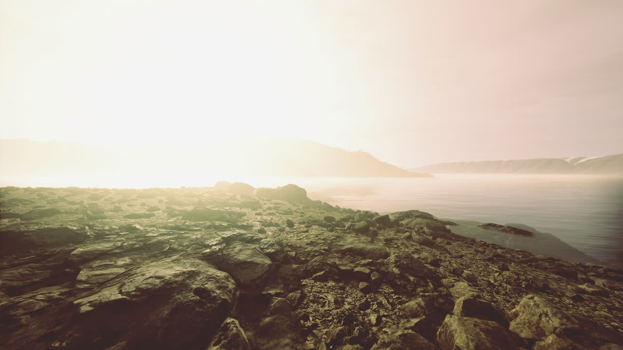 Sunlit shoreline revealing tranquil waters and distant hills at dawn