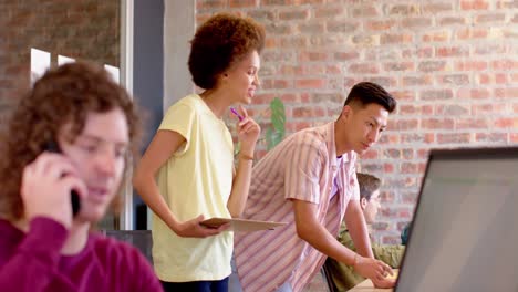 happy diverse female and male creatives in casual discussion standing at desk, slow motion