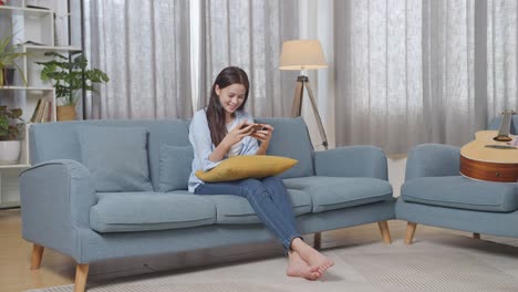 teenage girl relaxing on couch and playing phone