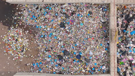 aerial over tins and plastic garbage bags at landfill with birds scavenging