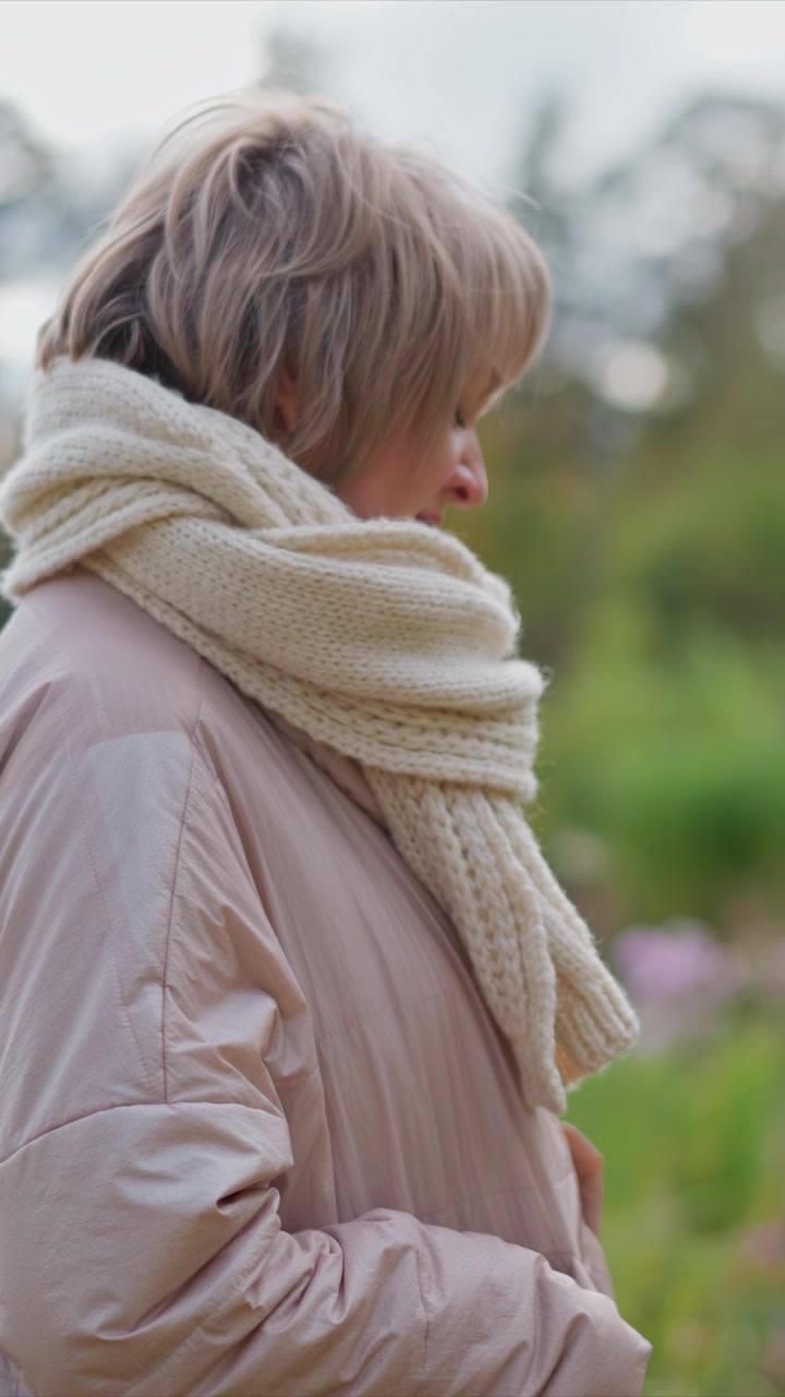 Primo piano della parte inferiore del corpo e dei piedi di una persona che cammina lentamente tra vivaci crochi viola, con erba verde visibile intorno. Messa a fuoco morbida sulle foglie autunnali in fiore in varie tonalità