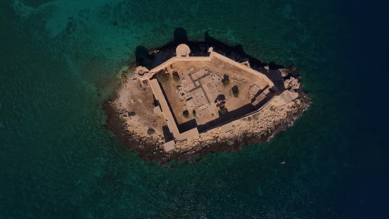 Kystfestning i dagslys med utsikt over rolig sjø og passerende yacht