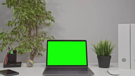 hombre caucásico usando una pantalla verde de portátil en el escritorio de casa.
