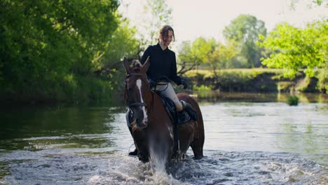 woman horseback riding through a river