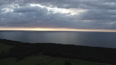 Drone-shot-of-seaside-and-beach-surrounded-by-dense-woods-on-a-sunny-day