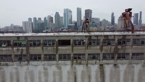 Vuelo-Hacia-Un-Edificio-Abandonado,-El-Horizonte-De-Montreal-Al-Fondo