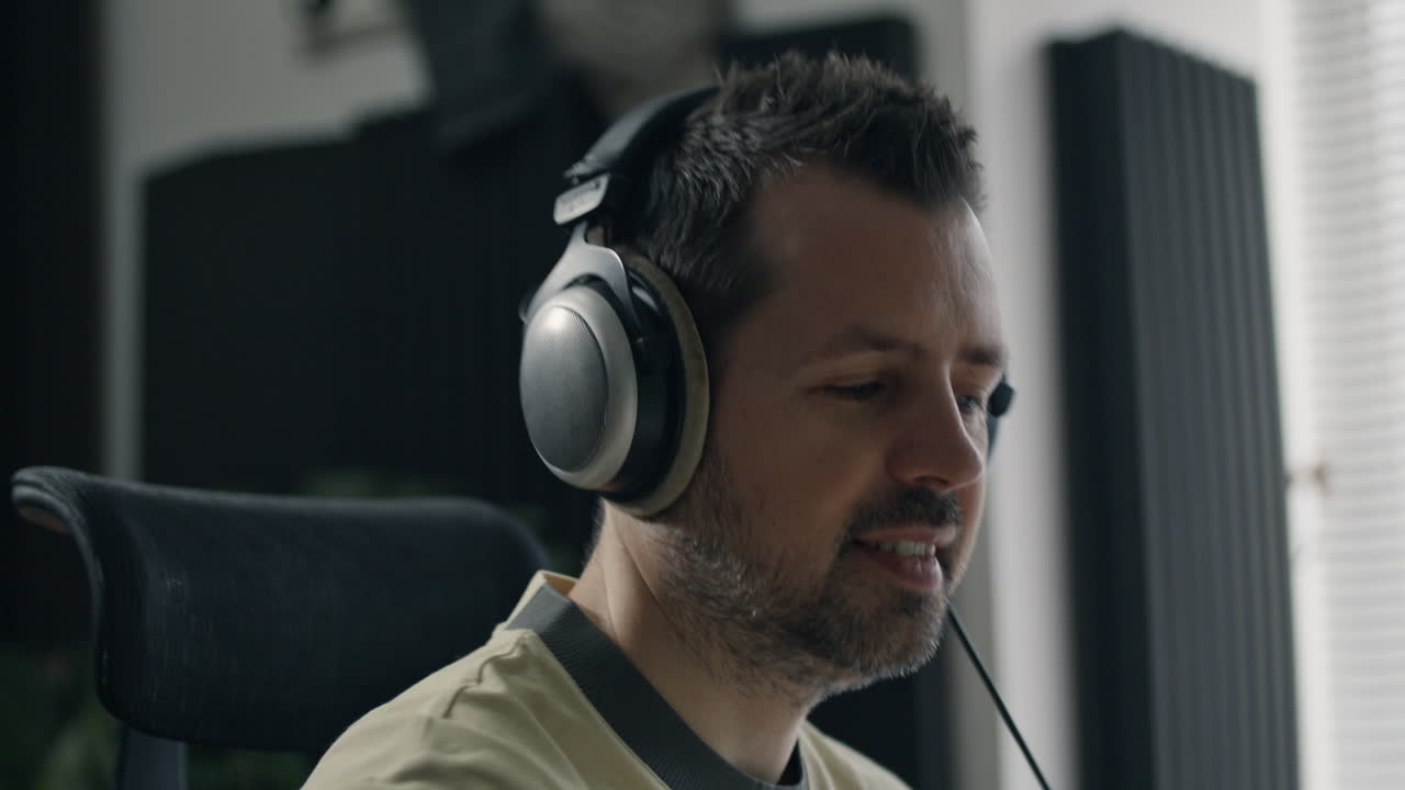 Music producer smiles while wearing headphones and working in acoustically treated studio