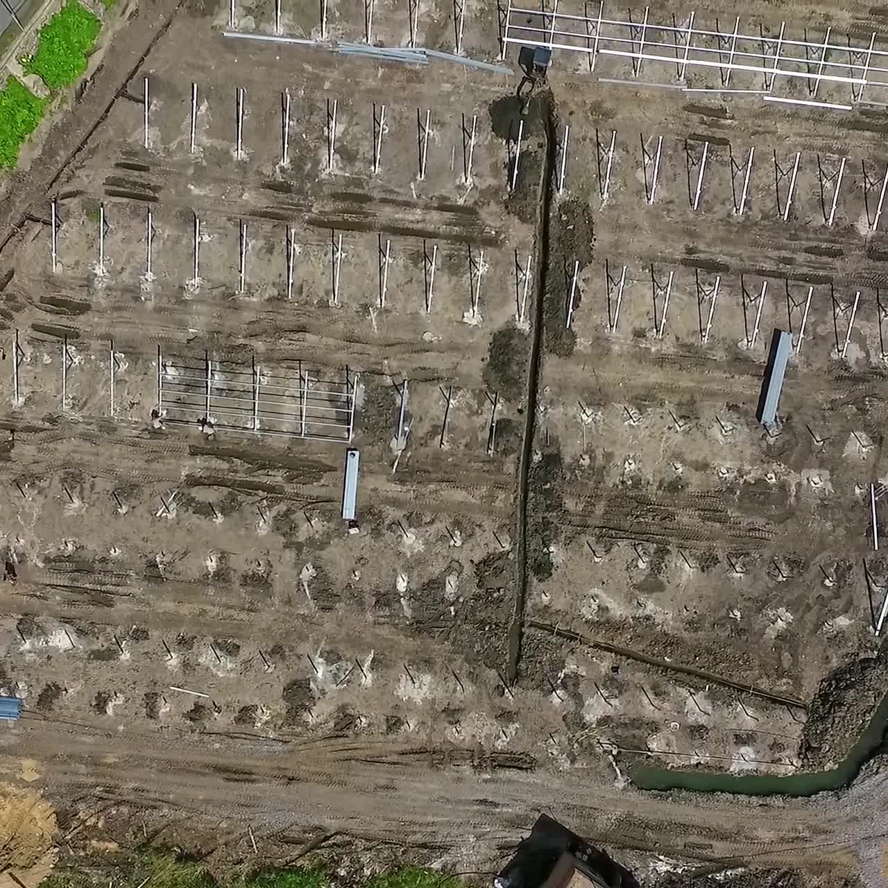 Quick rise over the grey ground with installed metal constructions. Territory prepared for solar power station building. Top view