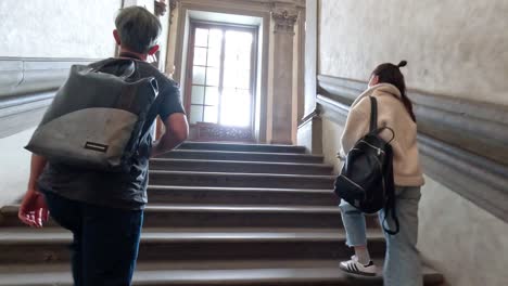 two people climbing stairs towards a window