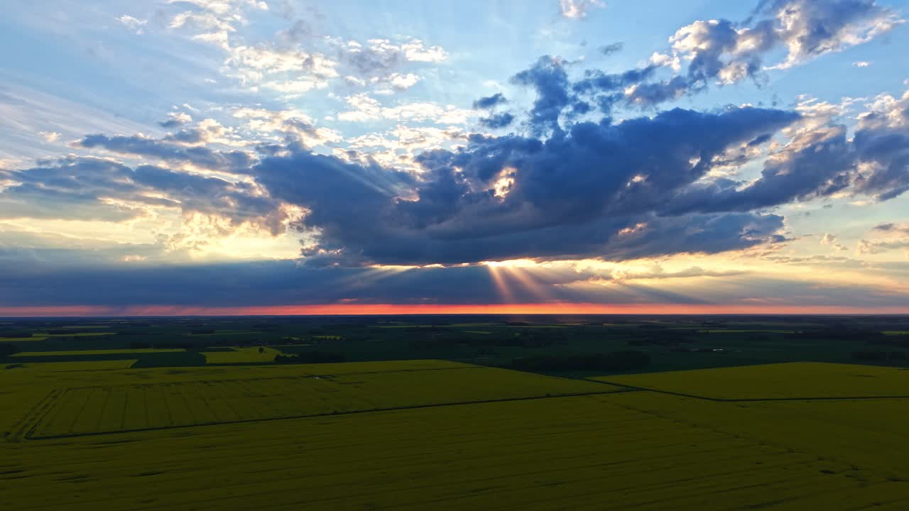 Drone of sun setting behind field and treeline horizon