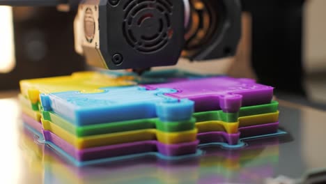 in a creative workshop, a 3d printer works diligently to produce vibrant puzzle pieces in shades of blue, purple, and yellow, showcasing advanced design technology and craftsmanship.