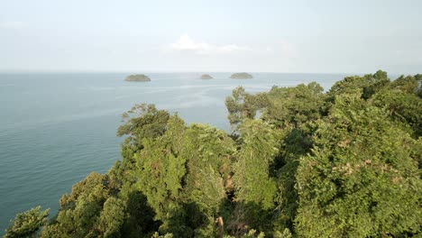 aerial-reverse-shot-of-rainforest-with-ocean-and-islands-in-the-distance,-Koh-Chang,-Thailand,-shot-at-sunrise