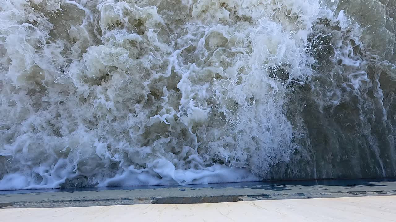 una gran ola chocando contra una orilla del río