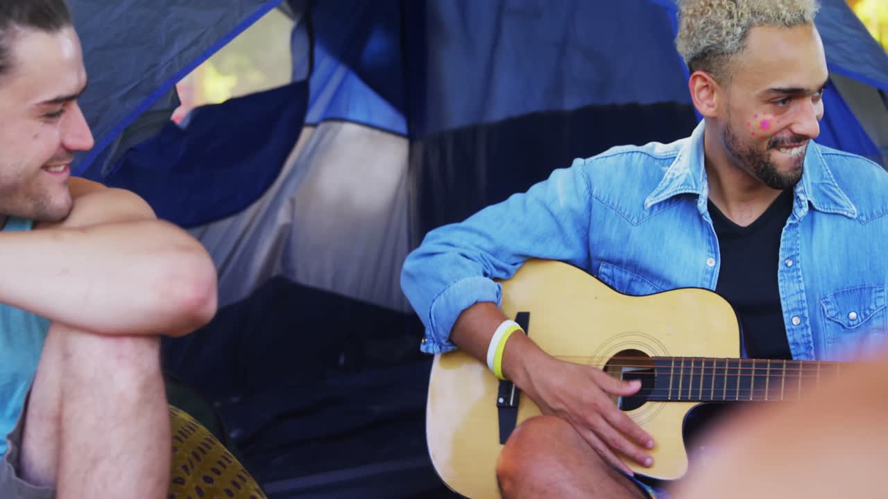 Uomo che suona la chitarra per i suoi amici a un festival musicale 4k