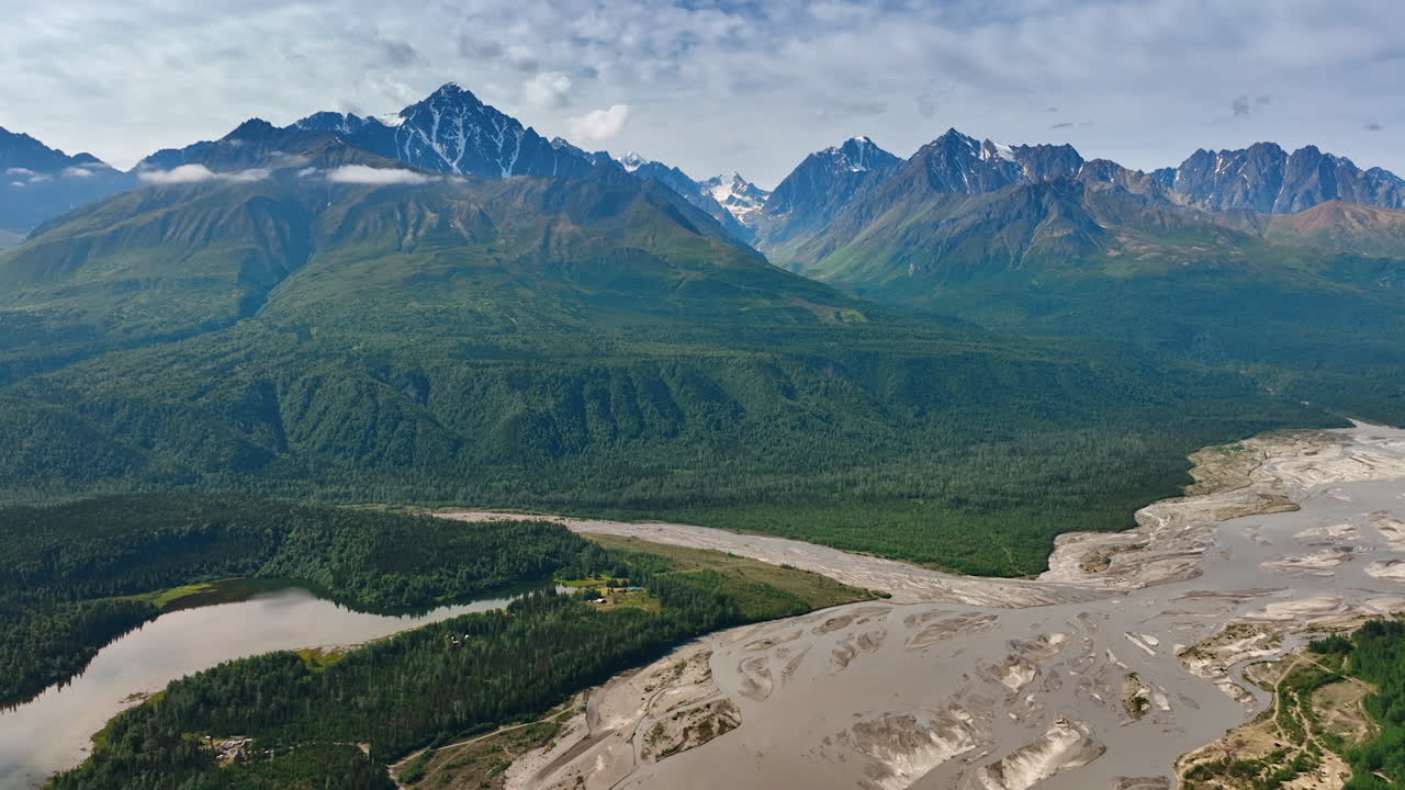 Stunning Alaska mountains and rivers. Majestic mountains rise above lush forests and winding rivers in the stunning Alaskan wilderness during daylight