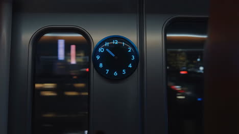 a glowing blue clock inside a train at night
