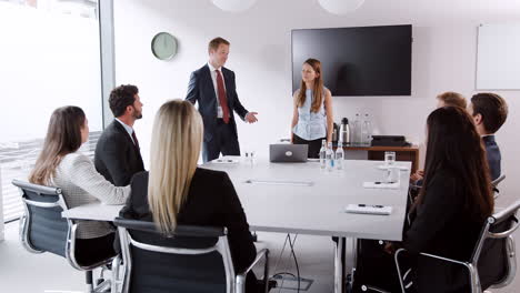 Young-Businessman-And-Businesswoman-Addressing-Group-Meeting-Around-Table-At-Graduate-Recruitment-Assessment-Day