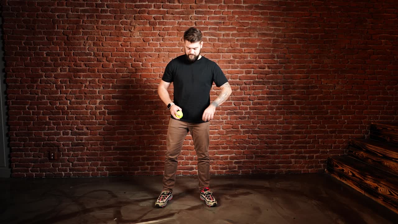 el hombre cambia de posición y continúa lanzando y atrapando la pelota de tenis.