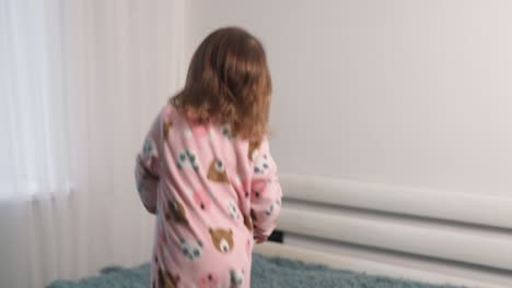 joyful two-year-old girl jumps on the bed in the bedroom