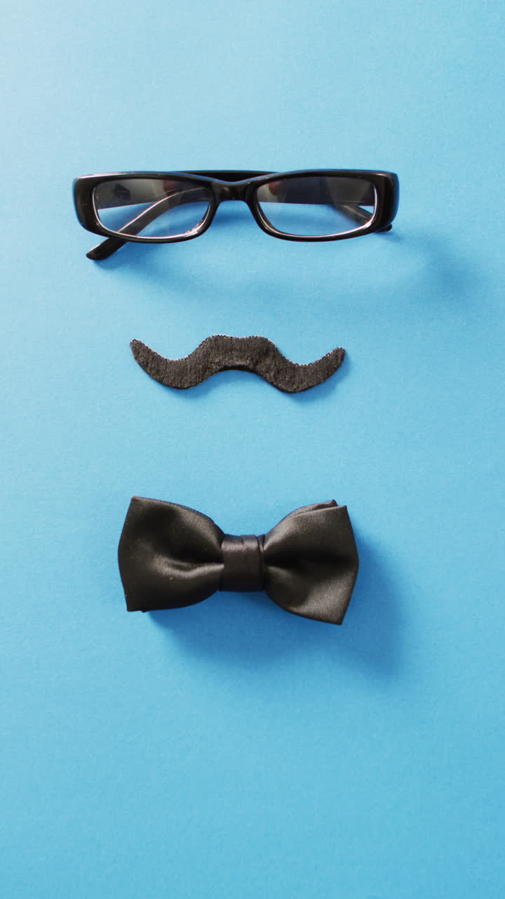 video vertical de bigote falso negro, gafas y pajarita en fondo azul con espacio para copiar