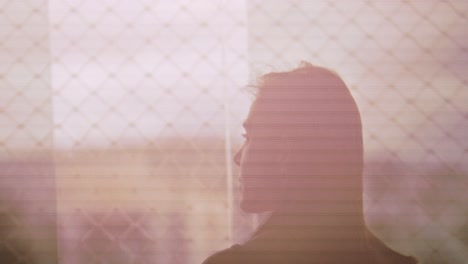 silhouette of woman looking outside apartment window in the morning, slow motion