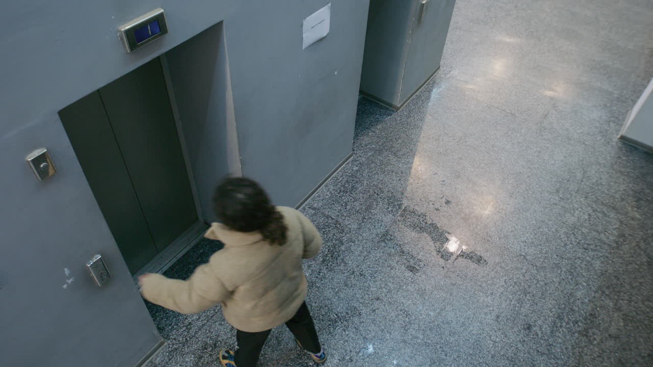 Person Waiting for an Elevator in a Modern Building Hallway