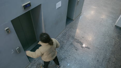 person waiting for an elevator in a modern building hallway