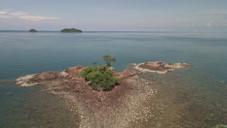 4k aerial rotating around small rocky island with isolated tree in thailand