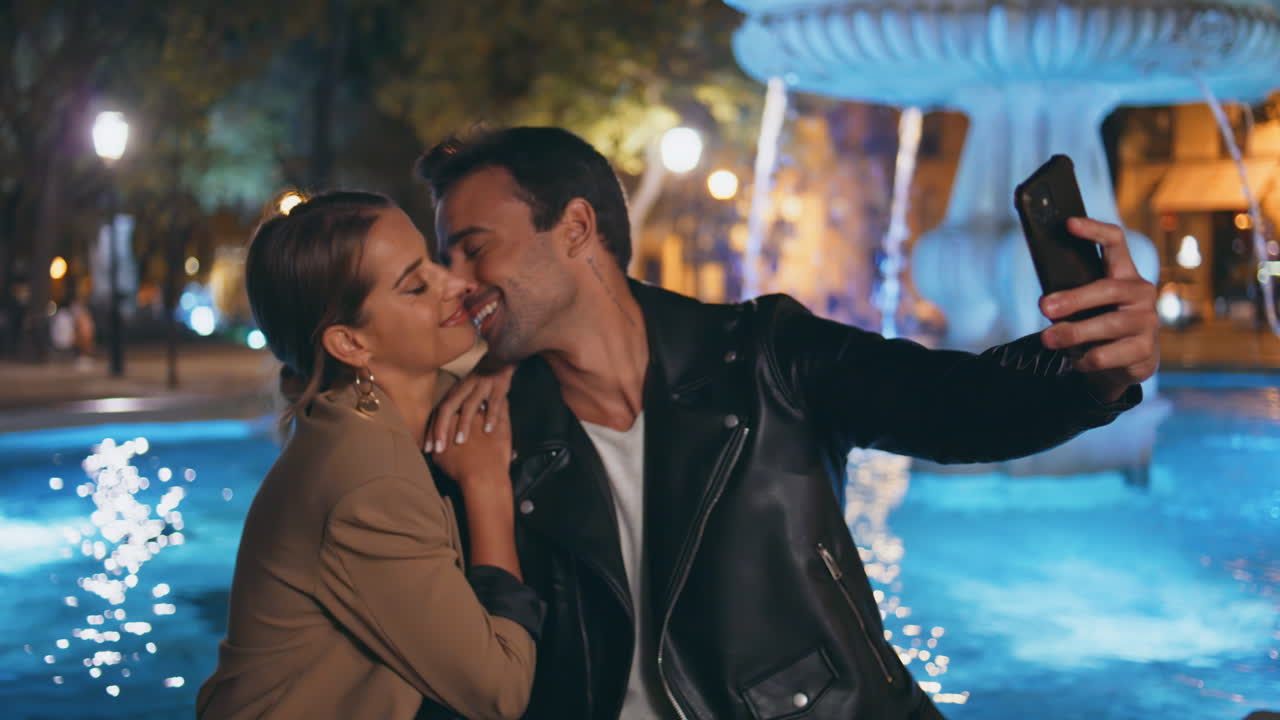 Beautiful lovers making photo on urban night date closeup. Smiling couple kiss