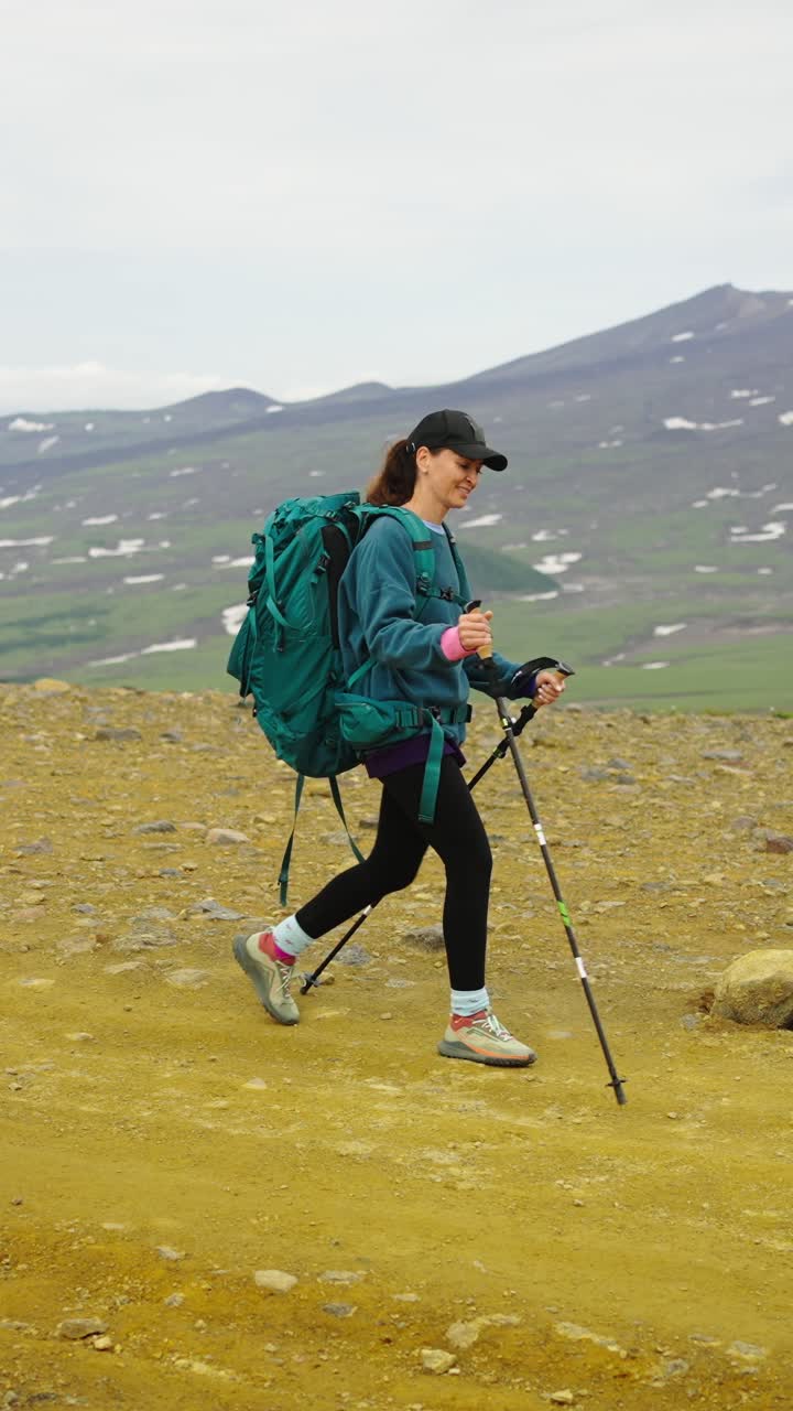 Donna che fa escursioni con zaino e bastoncini da trekking in un paesaggio montano