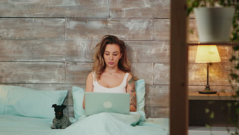 beautiful young woman in pajamas working on laptop