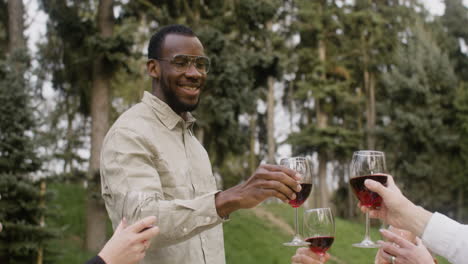 man standing in front of a table toasting with his friends at an outdoor party in the park 2