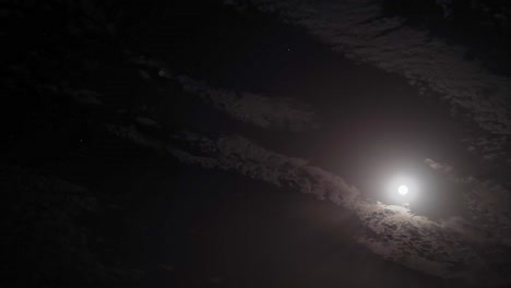 timelapse. night sky. moonlight between fast-moving clouds. moon and stars between cloud clusters moving across the sky