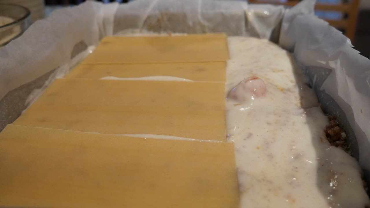 montaje de lasaña, poniendo láminas de pasta encima de la salsa bechamel